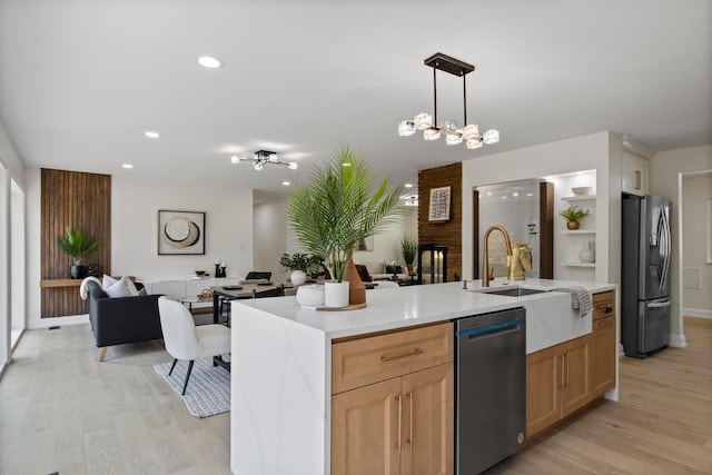 kitchen with light wood finished floors, decorative light fixtures, open floor plan, light countertops, and appliances with stainless steel finishes