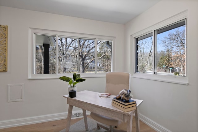 office space featuring plenty of natural light, wood finished floors, and baseboards