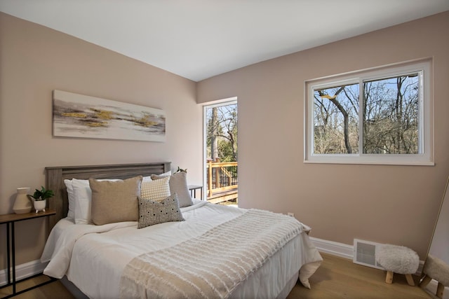 bedroom with access to outside, visible vents, baseboards, and wood finished floors