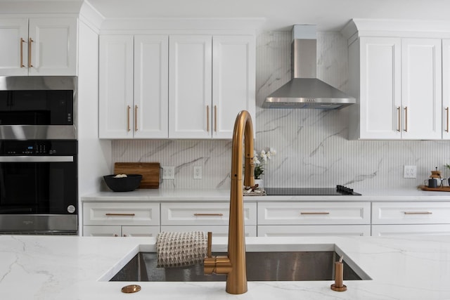 kitchen with stainless steel appliances, white cabinetry, decorative backsplash, and wall chimney range hood