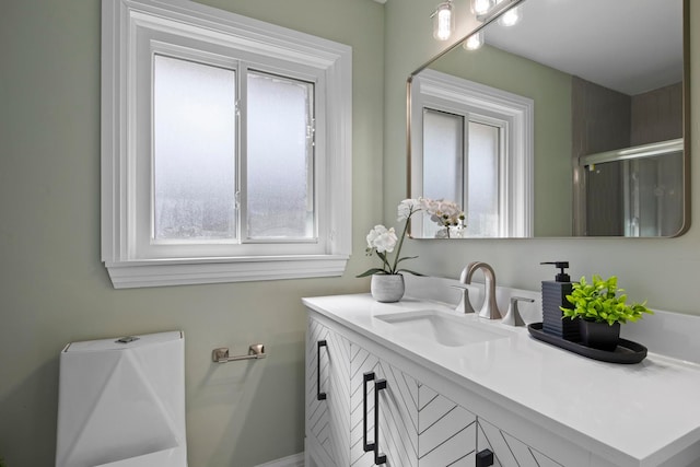 bathroom featuring a shower with shower door, a healthy amount of sunlight, and vanity