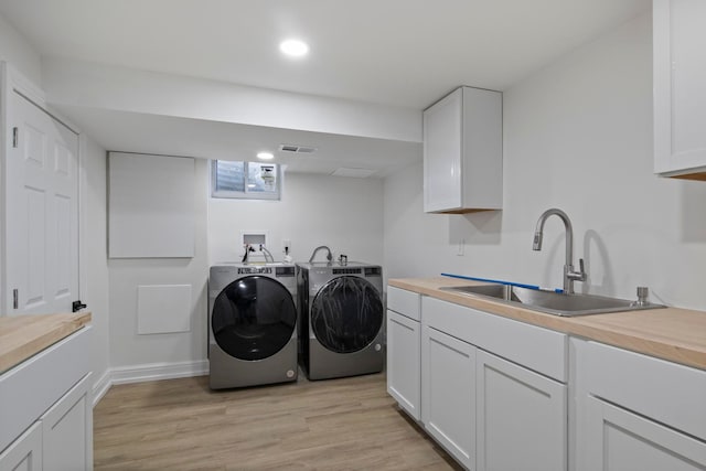 washroom with light wood-type flooring, a sink, washing machine and dryer, recessed lighting, and cabinet space