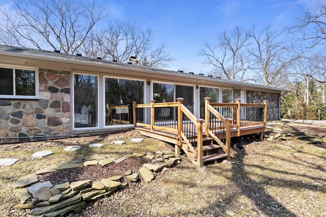 rear view of property with stone siding and a deck