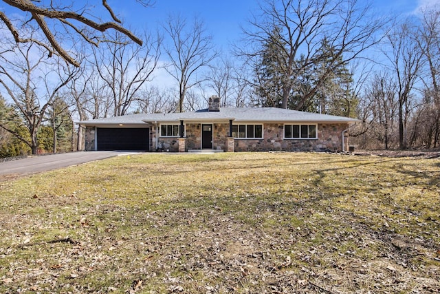 view of front of property with driveway, a chimney, a front lawn, stone siding, and a garage