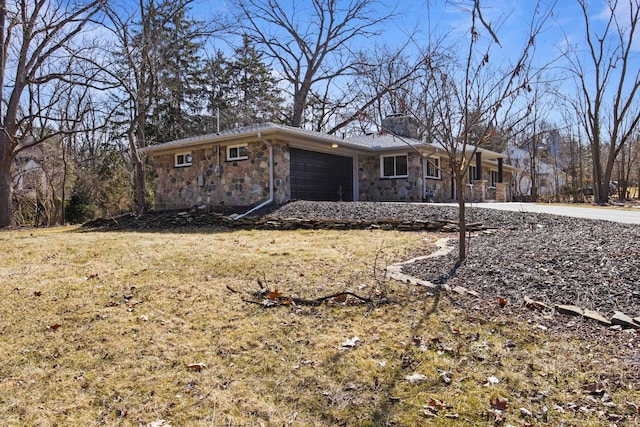 view of front of home featuring stone siding, a front lawn, a chimney, and a garage