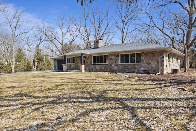 view of front of home featuring a front lawn, a chimney, driveway, stone siding, and an attached garage