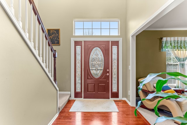 foyer with stairs, a high ceiling, baseboards, and wood-type flooring