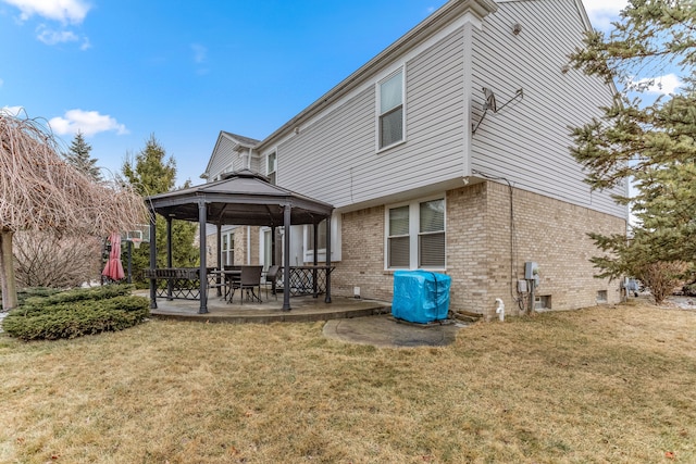 rear view of property with a gazebo, a patio, brick siding, and a lawn