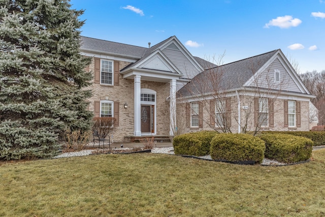 greek revival house featuring a front lawn, brick siding, and a shingled roof