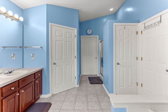 bathroom with vanity, tile patterned floors, baseboards, and a stall shower