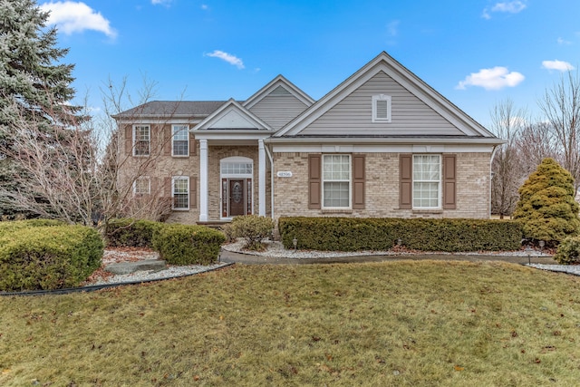 greek revival inspired property with a front yard and brick siding