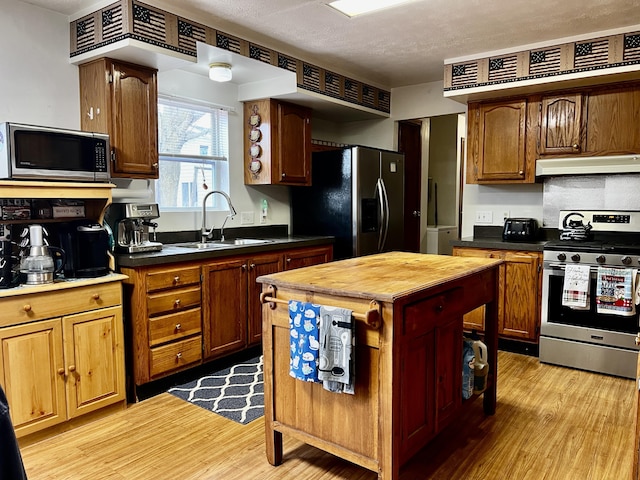 kitchen featuring wooden counters, light wood-style flooring, a sink, stainless steel appliances, and under cabinet range hood