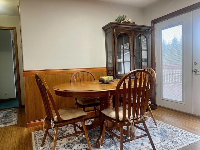 dining area with a healthy amount of sunlight, a wainscoted wall, and light wood-type flooring