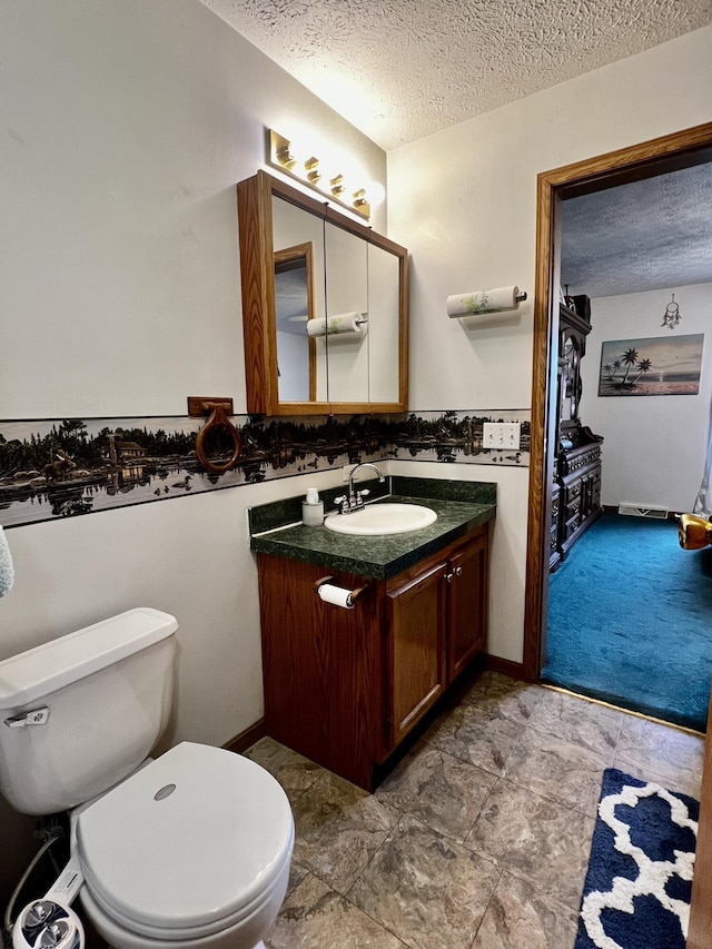 half bath with toilet, a textured ceiling, and vanity