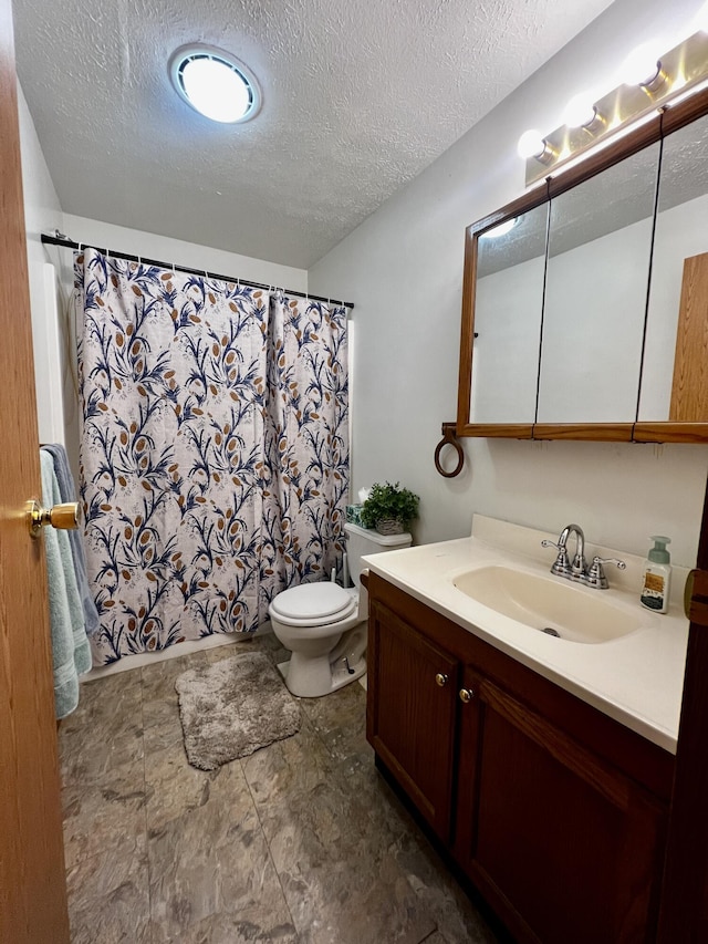 full bath featuring curtained shower, toilet, vanity, and a textured ceiling