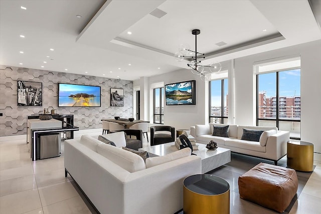 living area with a notable chandelier, recessed lighting, an accent wall, and a tray ceiling