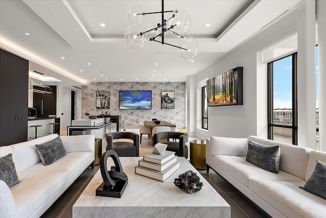 living room with an accent wall, a tray ceiling, and recessed lighting