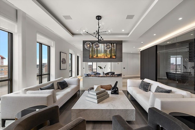 sunken living room with a tray ceiling, recessed lighting, visible vents, and a chandelier