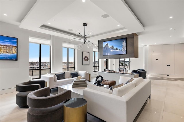 living room with recessed lighting, a tray ceiling, a healthy amount of sunlight, and a chandelier