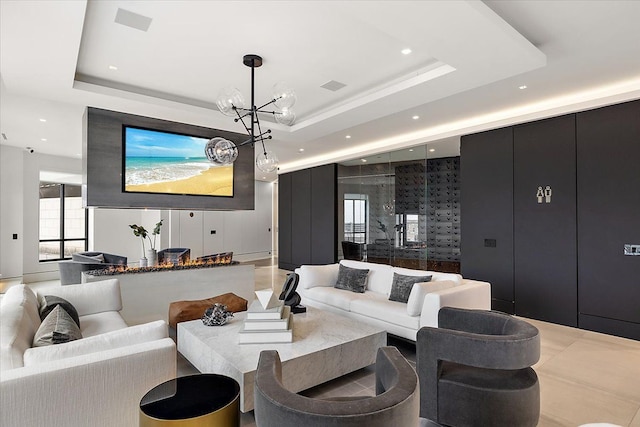 living room with recessed lighting, a raised ceiling, a notable chandelier, and a decorative wall