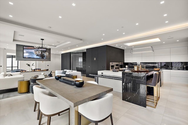 dining room featuring recessed lighting, a raised ceiling, and light tile patterned floors