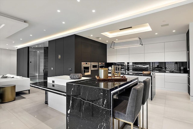 kitchen featuring a spacious island, dark countertops, backsplash, and modern cabinets