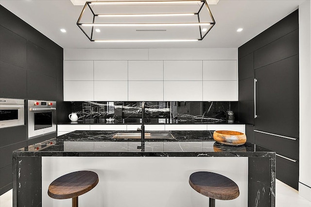 kitchen featuring stainless steel oven, modern cabinets, and dark cabinets