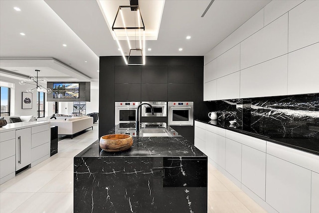 kitchen featuring light tile patterned flooring, decorative backsplash, open floor plan, and a sink