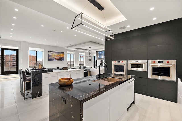 kitchen with a spacious island, oven, dark cabinetry, modern cabinets, and a sink