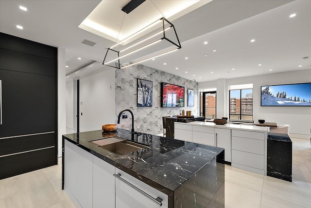 kitchen with a sink, a large island, modern cabinets, and an accent wall