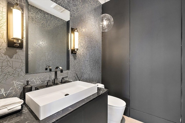 half bathroom with marble finish floor, vanity, toilet, and tile walls