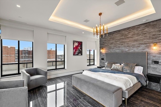 bedroom featuring visible vents, a raised ceiling, a notable chandelier, and an accent wall