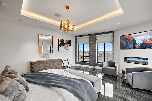 bedroom featuring visible vents, a tray ceiling, a glass covered fireplace, a notable chandelier, and baseboard heating