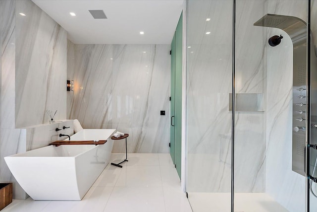 full bathroom featuring tile patterned floors, a sink, a marble finish shower, tile walls, and a soaking tub