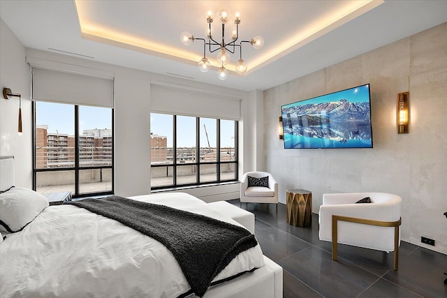 bedroom with a tray ceiling, dark tile patterned flooring, and a chandelier