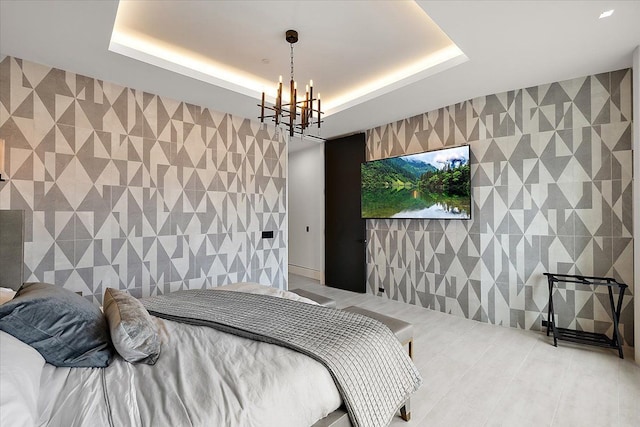 bedroom with a raised ceiling, tile walls, a chandelier, and an accent wall