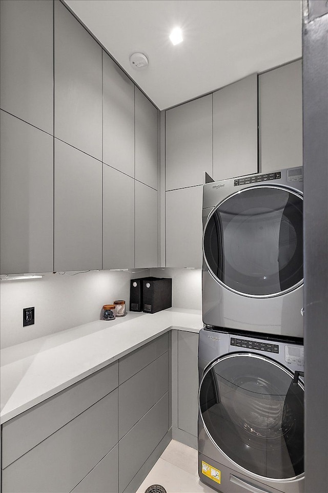 clothes washing area with cabinet space and stacked washer and clothes dryer