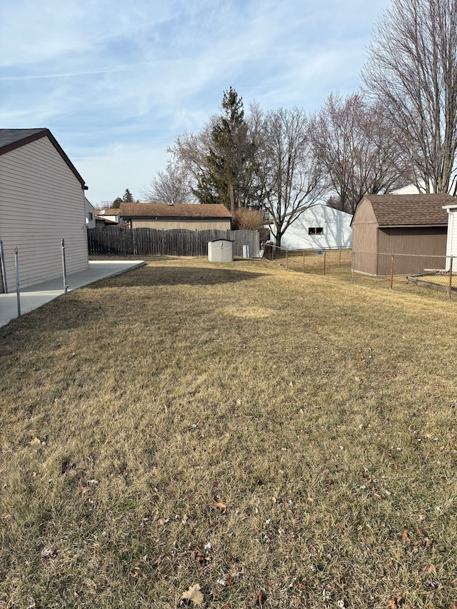 view of yard featuring a storage shed, a patio area, fence, and an outdoor structure