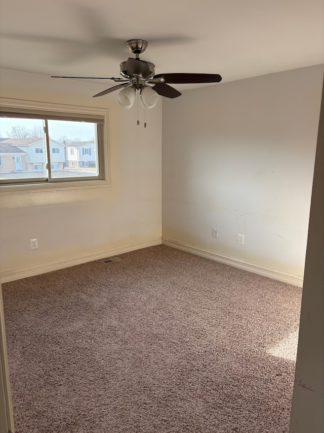 carpeted empty room featuring a ceiling fan and baseboards