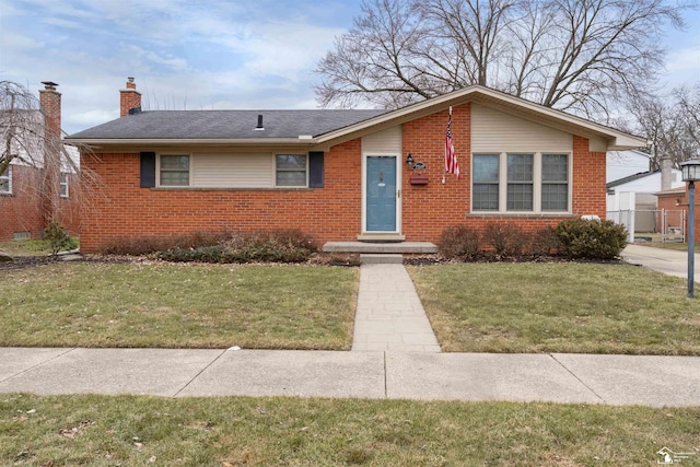 view of front of home featuring brick siding, a chimney, a front lawn, and roof with shingles