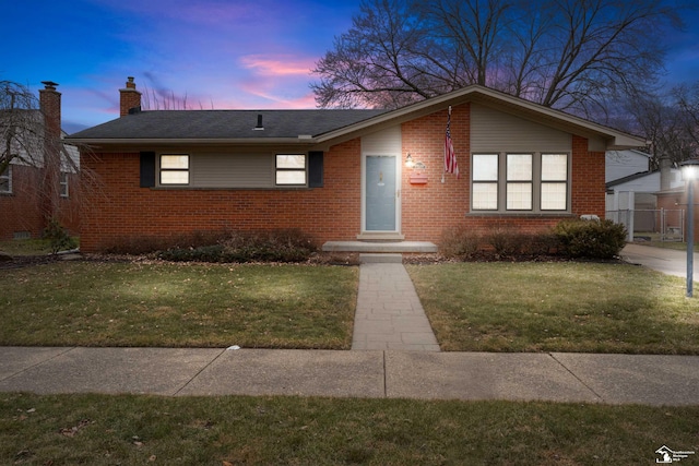 view of front of property featuring brick siding, a yard, and a chimney