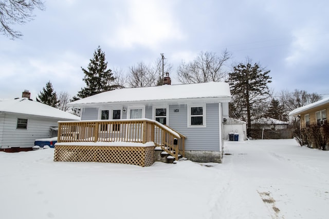 snow covered house featuring a deck and a chimney