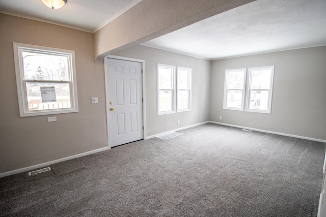 spare room featuring baseboards, visible vents, crown molding, and carpet flooring