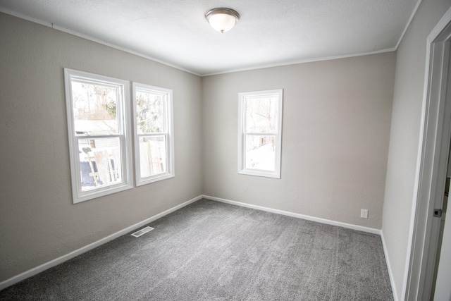 empty room with a textured wall, carpet floors, visible vents, and baseboards