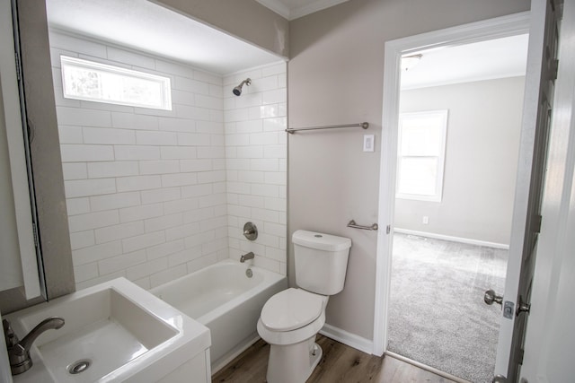 bathroom featuring toilet, a sink, wood finished floors, baseboards, and shower / bathing tub combination