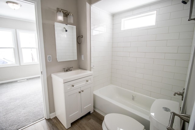 bathroom featuring baseboards, toilet, wood finished floors, vanity, and shower / washtub combination