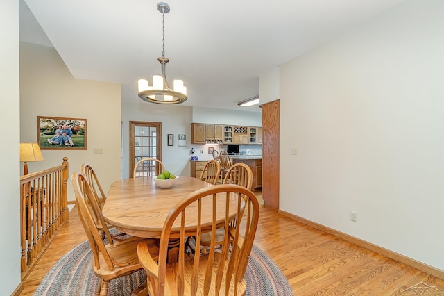 dining room featuring baseboards, light wood-style flooring, and an inviting chandelier