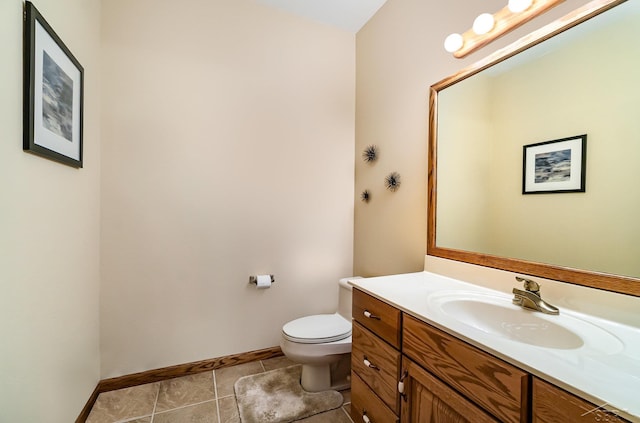 bathroom with tile patterned flooring, baseboards, vanity, and toilet