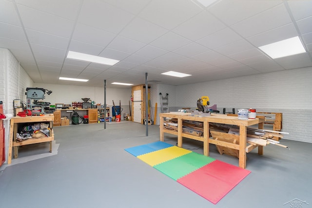 interior space with brick wall, a workshop area, and a paneled ceiling