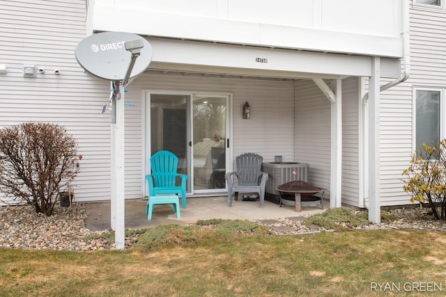 entrance to property with a patio, central AC unit, and a lawn